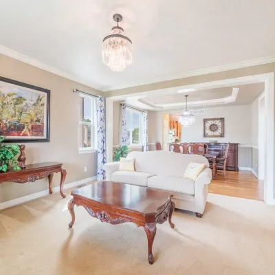 Traditional living room furniture including a carved wood coffee table, matching console table, and a cream-colored upholstered sofa.