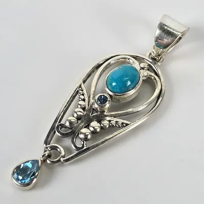Sterling silver pendant featuring an oval turquoise cabochon, a small round blue gemstone, and a dangling pear-cut blue topaz drop.