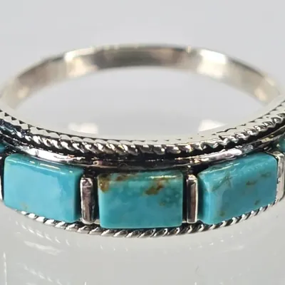 Sterling silver band ring featuring five rectangular turquoise inlay stones bordered by a twisted rope pattern, in a Southwestern style.