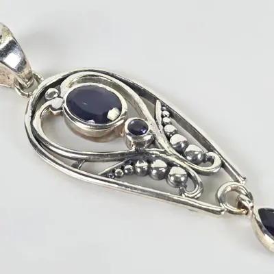 Sterling silver pendant featuring an openwork filigree design set with three dark blue sapphire or iolite gemstones, including a teardrop...