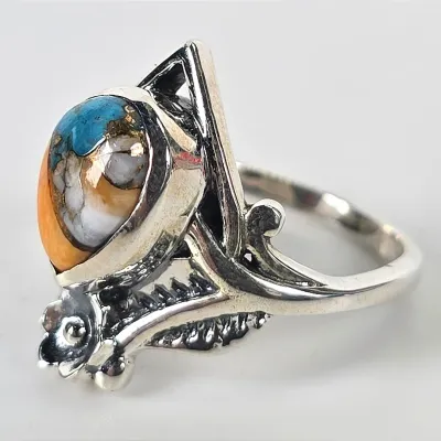 Sterling silver ring featuring a multi-colored spiny oyster and turquoise cabochon in a decorative, textured setting.