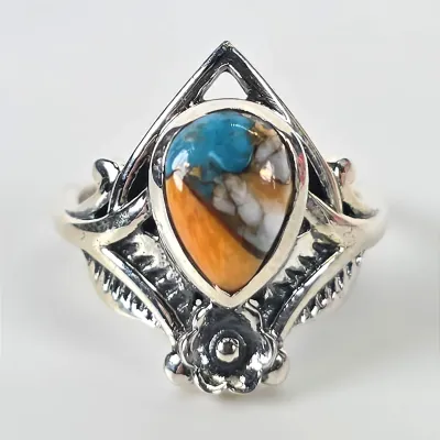 Sterling silver ring featuring a teardrop-shaped spiny oyster and turquoise composite cabochon, set in an ornate, openwork band with...