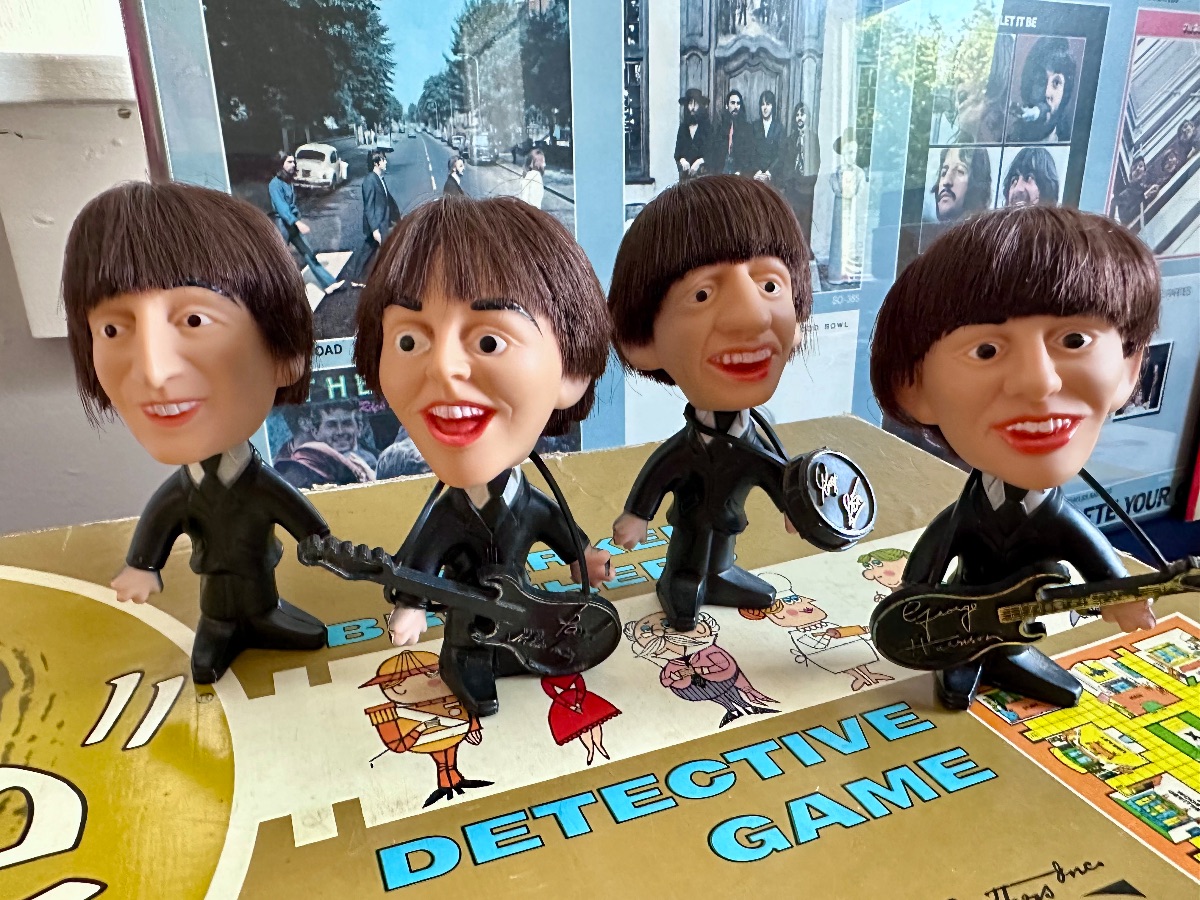 Vintage 1964 Remco Beatles bobblehead figures with synthetic hair and instruments, displayed on a vintage board game box.
