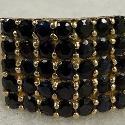 10k yellow gold cluster ring featuring a dense pavé or multi-row prong setting of deep, inky blue or