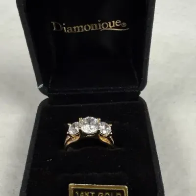 Diamonique three-stone ring featuring round-cut simulated diamonds set in a solid 14K yellow gold ba