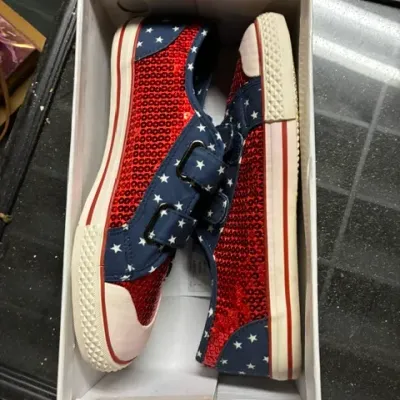 Pair of patriotic-themed sneakers featuring red sequins, blue canvas with white stars, and hook-and-loop strap closures, presented in...