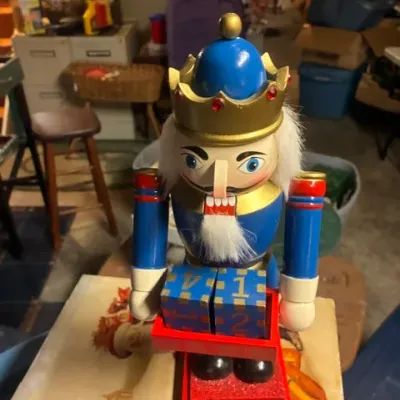 Vintage wooden Christmas nutcracker king holding a countdown calendar tray with blue numbered blocks, in good condition.
