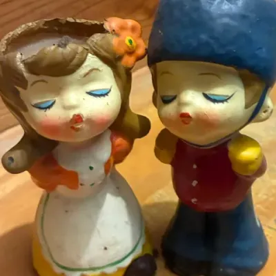 Vintage pair of hand-painted plaster or chalkware figurines depicting a kissing boy and girl, showing some wear and paint loss consistent...