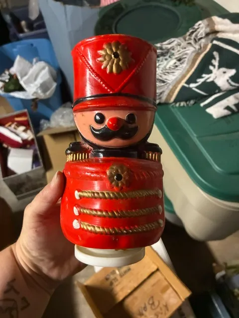Vintage plastic toy soldier bank in bright red and gold, featuring a hand-painted mustache and uniform details.