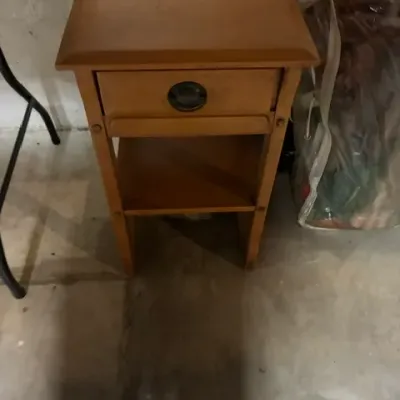 Mid-century modern style wooden nightstand featuring a single drawer with a recessed circular pull and an open lower shelf.