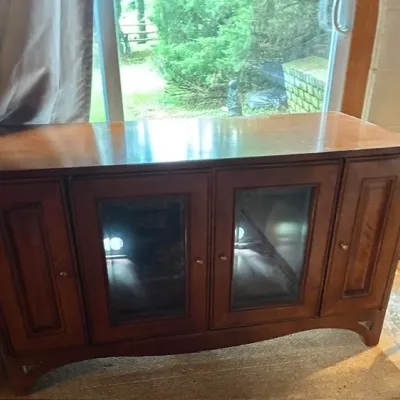 Vintage wooden media console or sideboard featuring two central glass-front doors and two flanking solid wood cabinet doors with brass...