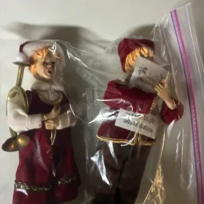Pair of vintage Christmas carolers figurines, featuring a girl with a horn and a boy holding sheet music, both dressed in red velvet...