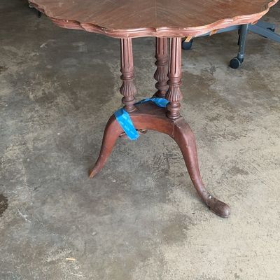Vintage wooden pedestal side table featuring a scalloped edge top, fluted legs, and a tripod base, showing some wear and blue tape on the...