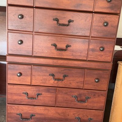 Traditional cherry wood chest-on-chest dresser featuring a multi-drawer configuration with dark metal bail pulls and round knobs.