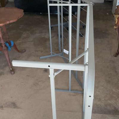 Light gray metal folding desk frame, shown standing on its side in a garage setting.