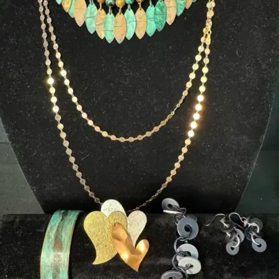 Assorted vintage fashion jewelry, including a green beaded fringe necklace, a gold-tone chain necklace with a multi-heart pendant, a...