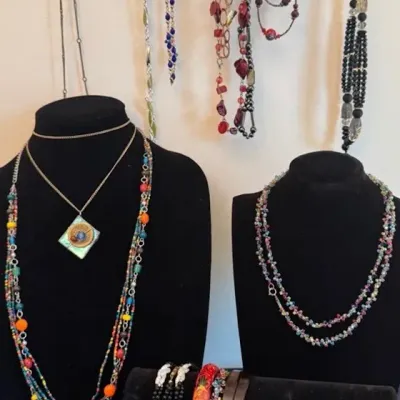 Assorted vintage costume jewelry, including beaded necklaces, pendant necklaces, and bracelets displayed on black velvet stands.