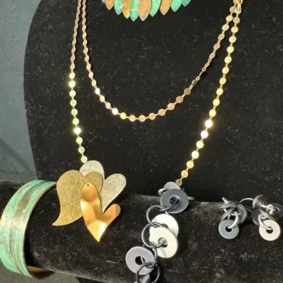 Assortment of vintage and artisan jewelry, including a green beaded collar necklace with leaf dangles, a gold-tone chain necklace with...