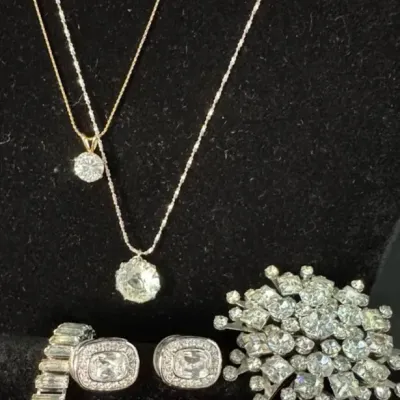 Assortment of costume jewelry including two pendant necklaces, a pair of cushion-cut stud earrings, a rhinestone-embellished bracelet,...