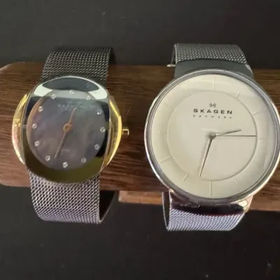 Two Skagen Denmark wristwatches with mesh bands, including a women's gold-tone model with a dark mother-of-pearl dial and a...