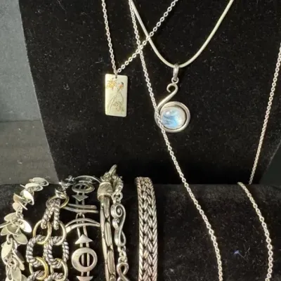 Collection of sterling silver jewelry, including a moonstone pendant necklace, a rectangular etched pendant, and various textured link...
