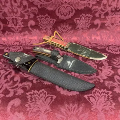 Three vintage hunting knives with sheaths, including a Winchester brand knife with a black nylon sheath and a knife with a leather sheath...
