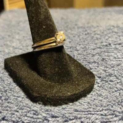 Classic diamond solitaire engagement ring paired with a matching simple wedding band, displayed on a black velvet ring stand.