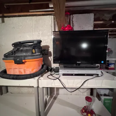 Toshiba flat-screen television paired with a silver DVD player, alongside a Ridgid wet/dry shop vacuum on plastic shelving units.