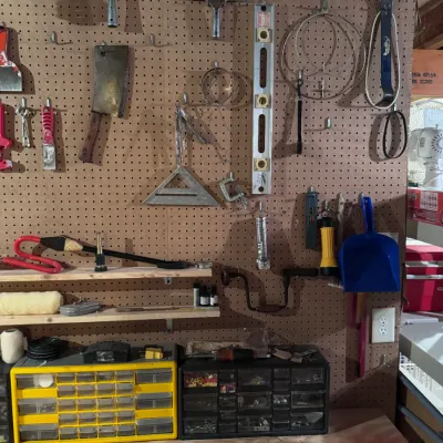 Assorted workshop hand tools and organization supplies, including a vintage meat cleaver, a Stanley level, a hand brace drill, squeegees,...