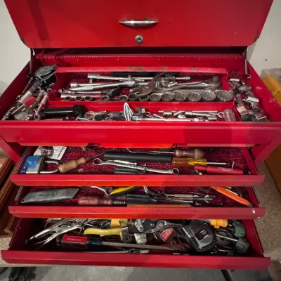 Stack-On red metal tool chest, made in the USA, featuring three drawers and a top compartment filled with an assortment of hand tools,...