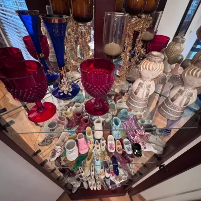 Vintage glassware and collectibles collection, featuring red Fenton hobnail goblets, hand-painted cobalt blue glass bud vases, and a...