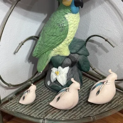 Vintage hand-painted ceramic parrot figurine perched on a stump, displayed alongside a trio of Southwestern-style ceramic quail figurines...