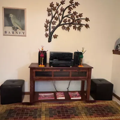Mission-style oak media console table featuring a lower shelf, flanked by two black faux-leather cube storage ottomans and topped with...