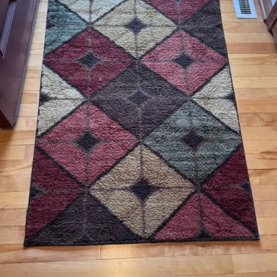 Contemporary geometric accent rug featuring a diamond and starburst pattern in shades of burgundy, brown, beige, and sage green, shown on...