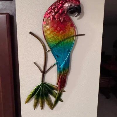 Vibrant metal parrot wall art, category: Home Decor, featuring a colorful rainbow-painted finish on a textured metal frame depicting a...