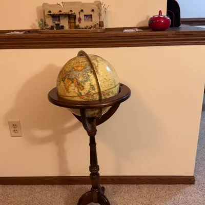 Vintage Replogle 12-inch floor globe on a turned mahogany tripod stand, featuring a raised-relief map and brass-finished meridian ring.