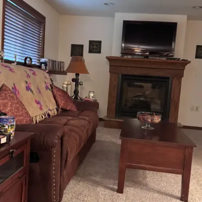 Cozy living room set featuring a brown microfiber reclining sofa with nailhead trim, a matching wooden coffee table, and a traditional...