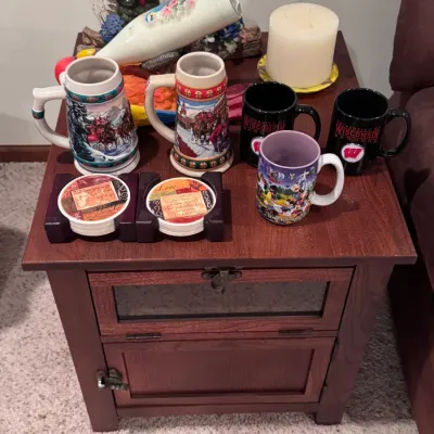 An assortment of collectible mugs, including Budweiser holiday steins, University of Wisconsin Badgers mugs, and a Walt Disney World mug,...