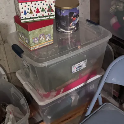 BellaNX 76-quart clear plastic storage bins with blue latching handles, stacked and topped with decorative holiday gift boxes and a...
