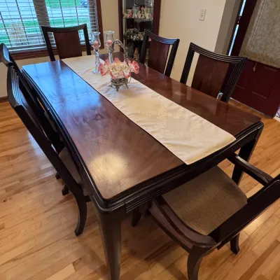 Contemporary dining room set featuring a dark-stained wood table with a polished top, accompanied by six matching high-back chairs with...