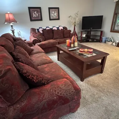Traditional living room furniture set featuring a matching burgundy paisley patterned sofa and loveseat, paired with a dark wood coffee...