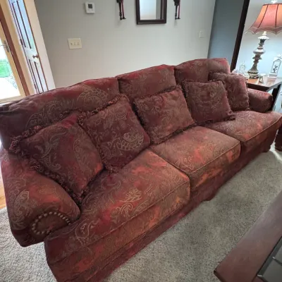 Traditional three-cushion sofa in a red and gold paisley brocade upholstery, featuring rolled arms with brass nailhead trim and matching...