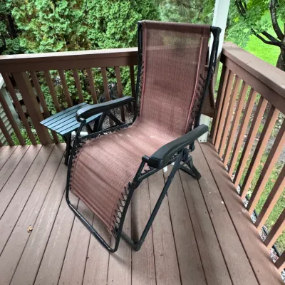 Lafuma zero gravity recliner chair, made in France, featuring a brown mesh sling seat laced to a black metal frame, shown on an outdoor...