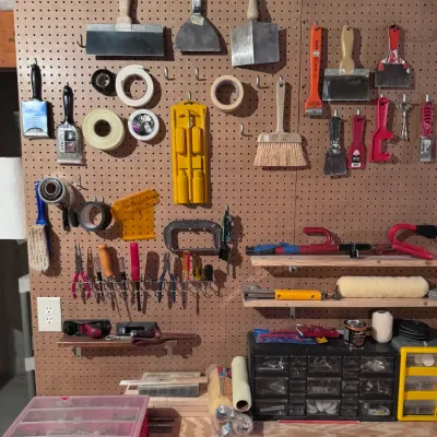 Assorted hand tools and workshop organization supplies, including putty knives, paintbrushes, tape, screwdrivers, and small parts...