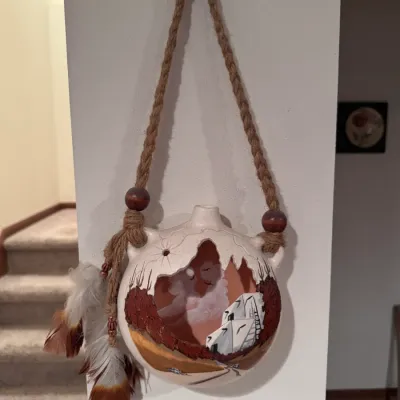 Hand-painted Southwestern ceramic story vessel wall hanging, featuring a cut-out design depicting a pueblo scene and a spirit face in the...