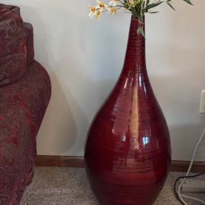 Large contemporary floor vase in a deep red lacquer finish with horizontal black banding, styled with faux white and yellow flowers.