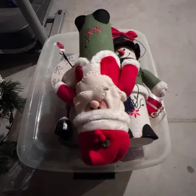 Vintage-style fabric Santa Claus and snowman figures, featuring felt and embroidery details, stored in a clear plastic bin.