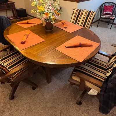 Cochrane Furniture oak dining set featuring a round pedestal table with butterfly inlay details and four rolling caster armchairs with...