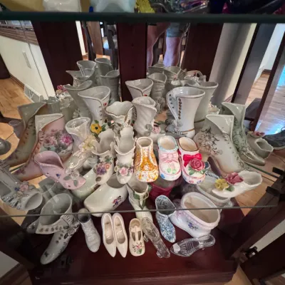 Collection of vintage porcelain and glass shoe figurines, featuring various styles including Victorian boots, slippers, and clogs with...
