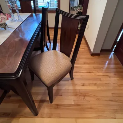 Contemporary dining chair featuring a dark wood frame with a fluted high back, a central wood veneer panel, and a neutral beige...
